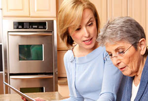 A caregiver helping a woman find online resources